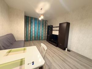 Apple city في Prigorodnyy: غرفة معيشة مع أريكة وطاولة وتلفزيون