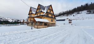 a large building in the snow with a snow covered road at Pokoje Gościnne Pod Grapą in Poronin