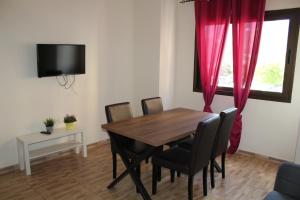 a dining room with a wooden table and red curtains at apartamentos la villa 3 in San Sebastián de la Gomera