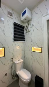 a bathroom with a toilet and a air conditioner on the wall at The White Residence, Jabi, Abuja in Abuja