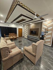 Noor Residence Designer Homes G15 في اسلام اباد: غرفة معيشة بها كنب وتلفزيون وطاولة