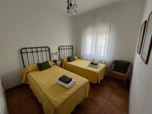 a bedroom with two beds and a chair at Casa rural collao de lobo in Serradilla