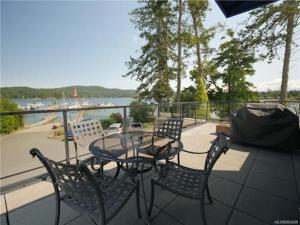 a table and chairs on a balcony with a view of the water at Sooke Harbour Penthouse - Luxurious 4 Bdrm Rental in Sooke