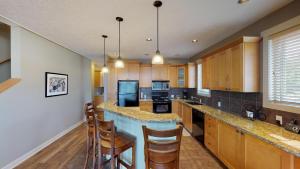 a kitchen with wooden cabinets and a island with bar stools at Sooke Harbour Penthouse in Sooke