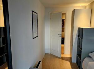 a room with a white wall with a door and a bedroom at Easy stay in Glostrup