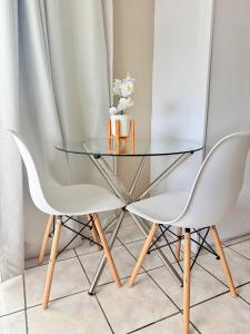a glass table and two white chairs in a room at Royaltics place in Weltevredenpark