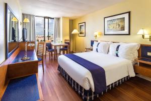 a hotel room with a large bed and a table at Holiday Inn Lisbon by IHG in Lisbon +195 photos