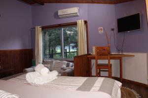 a bedroom with a bed and a desk and a window at Estero El Claro Hotel y Cabañas in Pucón