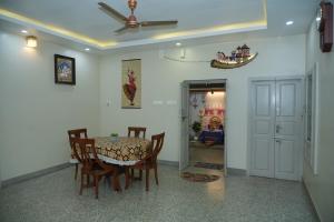 a dining room with a table and chairs and a ceiling fan at Brown Spring Home Stays in Thanjāvūr