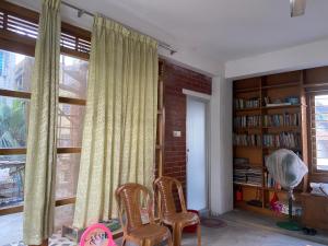 a living room with two chairs and a window at Rooftop Shantiniketon in Dhaka