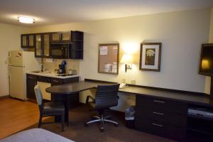 ウィチタにあるCandlewood Suites Wichita - Airport by IHGのテーブルと椅子と冷蔵庫のあるキッチン