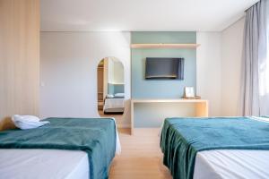 Pousada Encanto da Vila في بلوميناو: غرفة فندقية بسريرين وتلفزيون