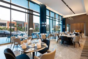 un ristorante con tavoli e sedie e grandi finestre di Crowne Plaza Al Jubail by IHG a Al Fanātīr