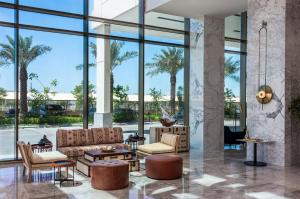 una hall con divano, sedie e ampie finestre di Crowne Plaza Al Jubail by IHG a Al Fanātīr