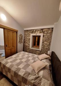 a bedroom with a large bed with a stone wall at CASA Kovac in Ljubuški