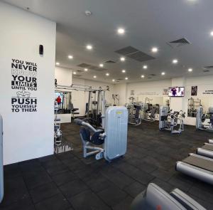 28th Floor Sky City View Apartment في إسكوبية: صالة ألعاب رياضية مع أجهزةٍ جري وأجهزة في الغرفة