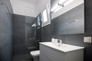 a bathroom with a sink and a toilet and a mirror at Perivola apartment in Patra +14 photos