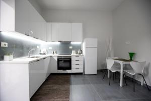 a white kitchen with a table and a refrigerator at Perivola apartment in Patra