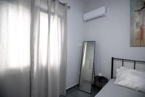 a bedroom with a bed and a window with a mirror at Perivola apartment in Patra