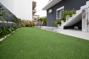 a yard with green grass next to a house at Perivola apartment in Patra