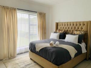 a bedroom with a large bed with a large window at 2 Bed 2 Bath Private Garden Apartment in Fourways