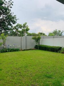 a fence in a yard with a green lawn at 2 Bed 2 Bath Private Garden Apartment in Fourways