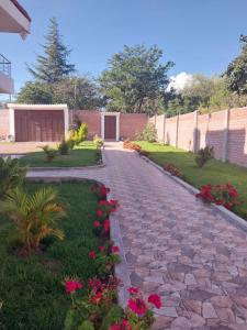um caminho de paralelepípedos em um jardim com flores cor-de-rosa em La Retama Houstime em Ayacucho