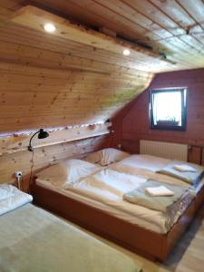 Dos camas en una habitación con techo de madera. en Koča na Pikovem, en Črna na Koroškem