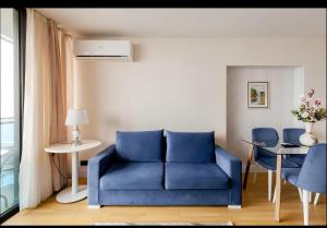 PANORAMA sea VIEW suite APARTMENTS في باتومي: أريكة زرقاء في غرفة مع طاولة وكراسي