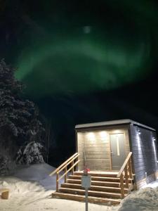 Una cabaña en la nieve con la aurora boreal verde en Arctic River View, en Rovaniemi