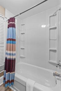 een witte badkamer met een bad en een douche bij Midstream Loft 2BR Parking W&D in St. John's