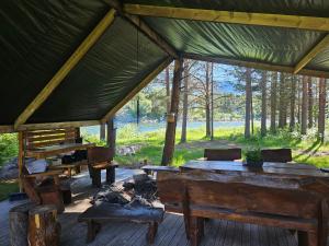 a pavilion with wooden tables and benches in a forest at Tørfoss Gård, Hytte utleie, Campingvogn og bobil plasser in Potka