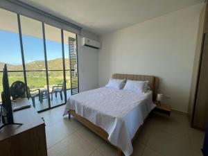 a bedroom with a bed and a balcony with a table at Edificio Salinas del Mar - Pozos Colorados in Santa Marta +80 photos