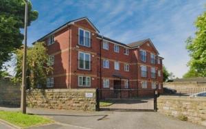 a large red brick building with a fence at Tarn House Apartment South Yorksire in Barnsley