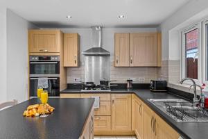 een keuken met houten kasten en een zwart aanrechtblad bij Spacious 5 Bed House in Reading by Amber Stays, Perfect for Business & Contractors, Sleeps 12 in Reading