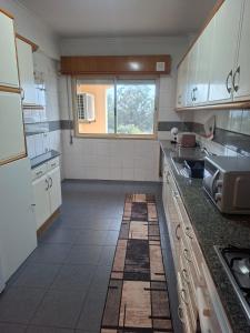 Una cocina con gabinetes blancos y piso de baldosas. en Deluxe Room Santarém, en Santarém