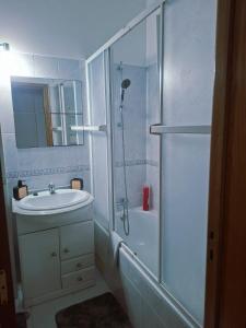 Un baño blanco con ducha y lavabo. en Deluxe Room Santarém, en Santarém