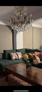 sala de estar con sofá verde y lámpara de araña en MZ Maison de la Place, en Eptalofos