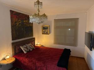 1 dormitorio con cama roja y lámpara de araña en MZ Maison de la Place, en Eptalofos