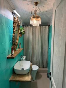 y baño con lavabo, espejo y lámpara de araña. en MZ Maison de la Place, en Eptalofos