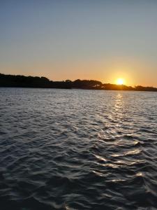 um pôr-do-sol sobre uma grande massa de água em camping do point lá na barra em Amontada