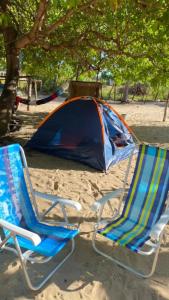 duas cadeiras de jardim e uma barraca em uma praia em camping do point lá na barra em Amontada