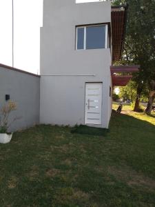 un edificio bianco con una porta nell'erba di JAS departamento a General Acha