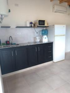 una cucina con armadi neri e frigorifero bianco di JAS departamento a General Acha Altre 3 foto