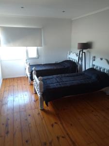 due letti in una stanza con pavimenti in legno di JAS departamento a General Acha