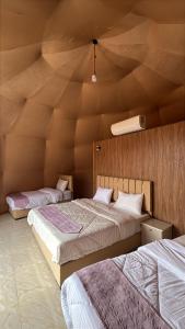 two beds in a room with a wooden ceiling at Wadi Rum Star Haven camp in Wadi Rum