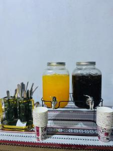 uma mesa com dois potes de geleia e xícaras em Malak rum camp em Wadi Rum