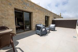 a patio with two chairs and tables on a brick wall at La MAISON DU VAL in Jbeil