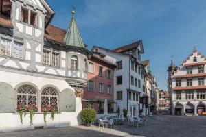 a city street with buildings and tables and chairs at Louisa's Loft - Auszeit in den Bergen & der Natur für Familien, Freunde und Paare - Wandern & Seen - 1h ab Zürich in Alt Sankt Johann