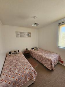 um quarto com duas camas e uma janela em Parque Mar Depto em El Tabo